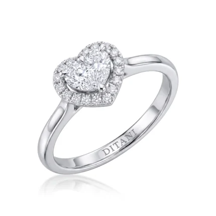 Engagement ring in white gold featuring a central round diamond with a heart-shaped diamond halo and small side diamonds on the halo, brand-inscribed band interior.