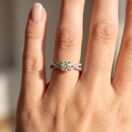 A close-up of a hand showing a silver ring with a large central diamond and twisted diamond-studded band on the ring finger