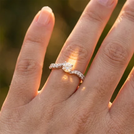 Close-up of a hand wearing a diamond engagement ring with a pavé band and a central stone on the ring finger.