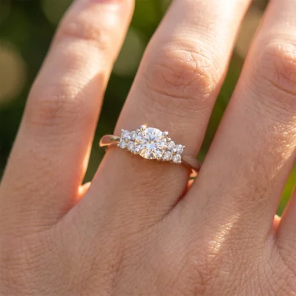 Diamond engagement ring on a finger with a central round diamond and pavé-set side stones on a rose-gold band
