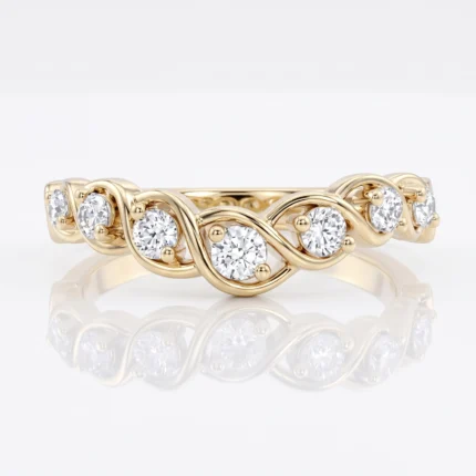 Gold ring with a flowing, wavy band set with round diamonds on a reflective white surface.