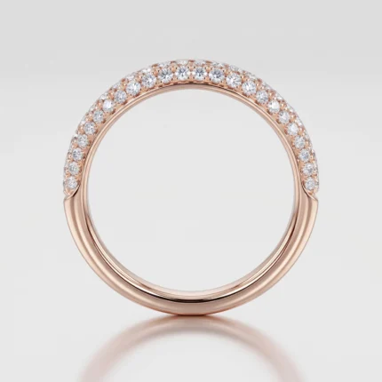 Rose gold ring with diamonds set along the upper half, shown on a white reflective backdrop.