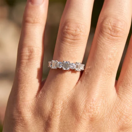 Close-up of a ring on a finger featuring alternating baguette and round diamonds.