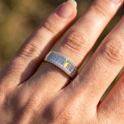 Close-up of a diamond-studded ring on a finger, featuring a row of baguette-cut stones with pavé edges.