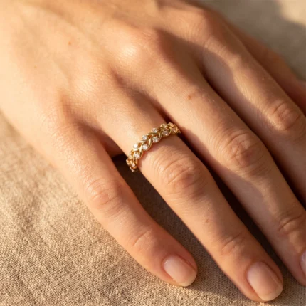 Close-up of a gold diamond-studded ring with interlocking links on a finger.