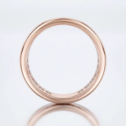 Rose gold ring with perforated inner edge, resting on a reflective surface.
