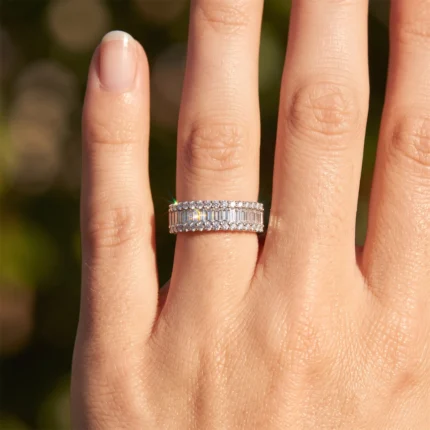 Close-up of a silver diamond-studded ring worn on the ring finger, showing two parallel rows of stones catching light in sunshine.