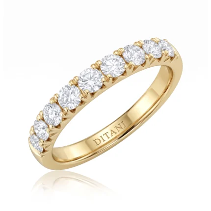 Yellow gold ring with a row of round-cut diamonds set in prongs along the top half of the band with a polished inner surface.