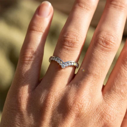 Close-up of a hand wearing a silver ring with a chevron-shaped row of diamonds on the ring finger