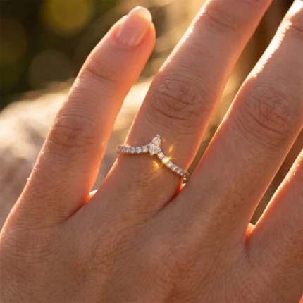 Diamond-studded split-ring with a small central stone on a finger, illuminated by warm sunlight.