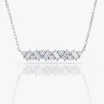 Silver necklace with a row of alternating round and baguette-cut diamonds on a chain, set in a curved design with a white background and soft reflection.