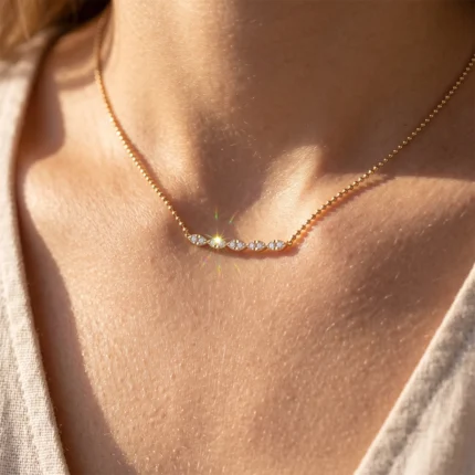 Gold necklace with a curved row of small diamonds resting on the collarbone area.