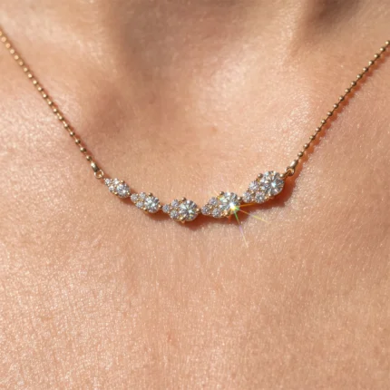 Close-up of a gold necklace with diamond flower clusters resting on bare skin.