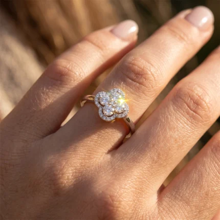 Gold ring featuring a four-petal diamond flower on the finger (close-up).