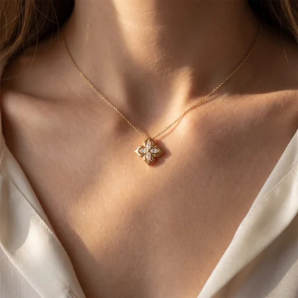 Gold chain necklace with diamond-encrusted four-leaf clover pendant resting on a bare neck.
