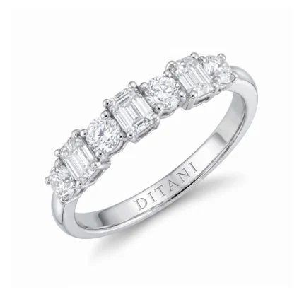 Silver ring with five alternating round and emerald-cut diamonds set along a polished band; brand name visible on the inner side.