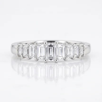 Silver ring featuring a row of rectangular baguette-cut diamonds along a polished band, with prongs at each stone's corners.