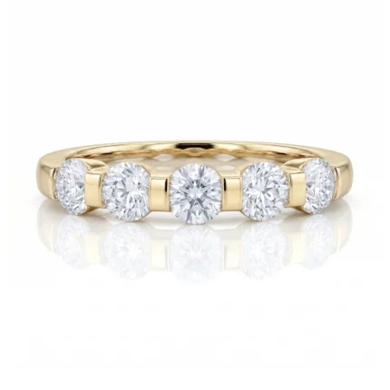 Gold band ring in yellow gold featuring five round, bezel-set diamonds in a row.