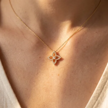 Gold chain necklace with a diamond-studded four-petal flower pendant resting on the neck