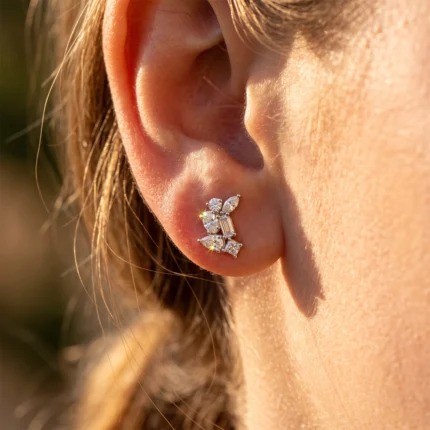 Close-up of a woman's ear with a sparkling diamond earring cluster on the earlobe.