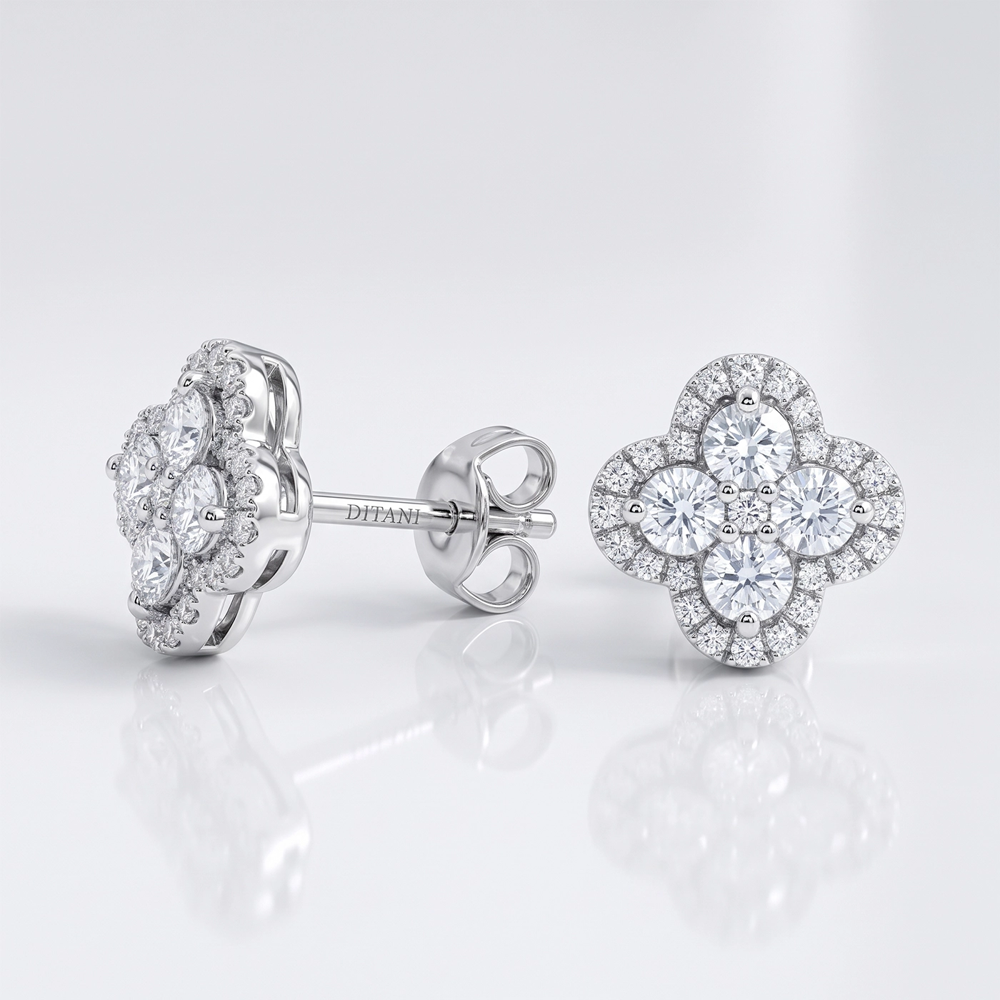 Златни обеци с диаманти DITANI 2 - DITANI Flower-shaped diamond stud earrings in white gold/silver with a central cluster and pavé-set stones, displayed on a reflective surface, brand name Ditani on the post.