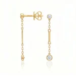Gold drop earrings with chain links and round diamond accents on a pale background.