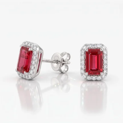 Emerald-cut ruby stud earrings with a diamond halo in white gold.