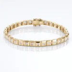 Gold bracelet with square-link sections set with small diamonds, on a white reflective surface.