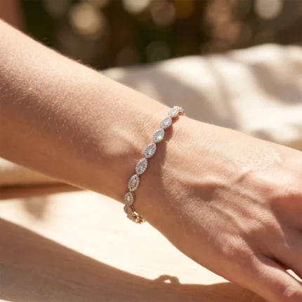 Diamond-encrusted oval-link bracelet on a bare wrist, highlighted by sunlight.
