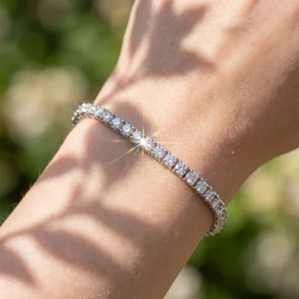 Close-up of a diamond tennis bracelet on a wrist, sparkling in bright sunlight outdoors.