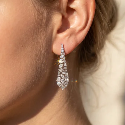 Close-up of a diamond drop earring on a woman's ear, sparkling in sunlight.
