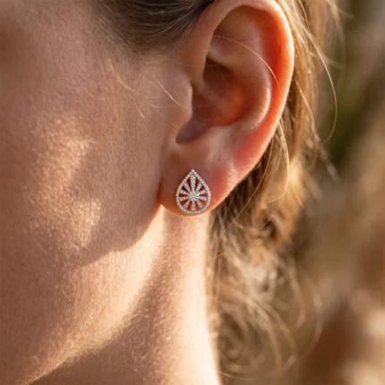 Close-up of a sparkling diamond teardrop earring with a sunburst cutout on the earlobe