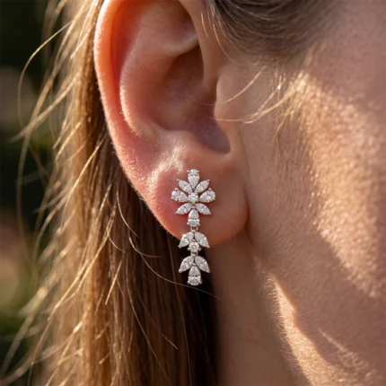 Close-up of an ear wearing a diamond floral drop earring on the earlobe.