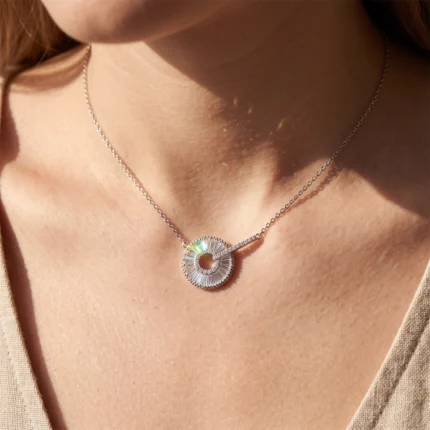 Silver circular sunburst pendant necklace with a dotted inner ring, on a delicate chain.
