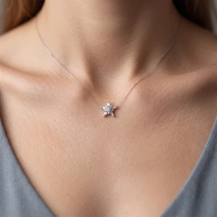 Silver star pendant necklace with small crystals resting on a woman's collarbone.