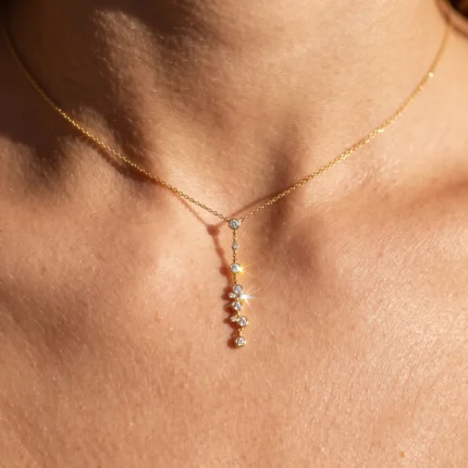 Gold necklace with a small diamond-studded drop pendant resting on the neck