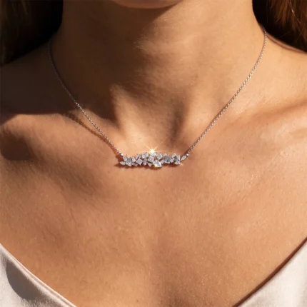 Silver chain necklace with a row of diamond-like leaf shapes resting on the collarbone.
