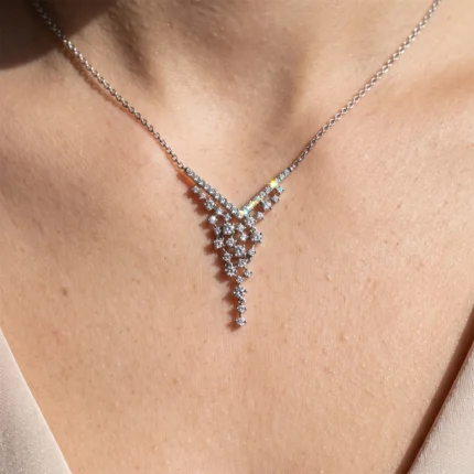 Elegant silver necklace with a V-shaped diamond pendant resting on the collarbone, sparkling stones on a fine chain.