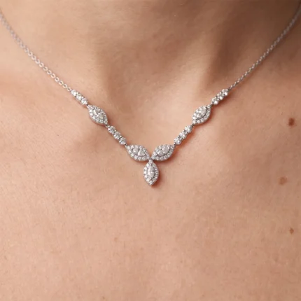 Silver necklace with diamond leaf-shaped pendants resting on a bare neck.