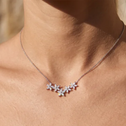 Silver necklace with five petal-shaped diamond clusters resting on the collarbone.