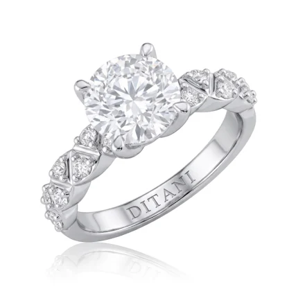 Engagement ring with a large round center diamond and pavé-set diamonds along the shoulders; band engraved with DITANI.