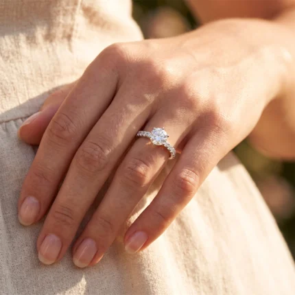 Close-up of a hand wearing a diamond engagement ring with a round center stone and pavé band.