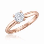 Rose gold solitaire engagement ring with a round diamond held by four prongs and 'DITANI' engraved on the band