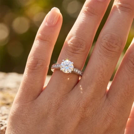 Close-up of a diamond engagement ring on a finger with sunlight creating a sparkle on the center stone.