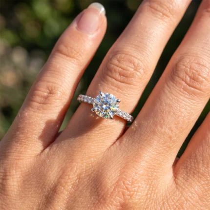 Engagement ring with a large round-cut diamond on the ring finger, pavé-set band catching sunlight.