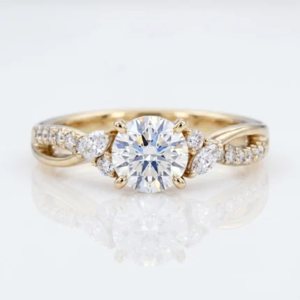 Gold engagement ring with a round-cut center diamond held by four prongs, flanked by smaller diamonds along the band.
