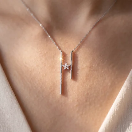 Silver necklace with two vertical bar pendants and a small diamond flower centerpiece resting on the chest.