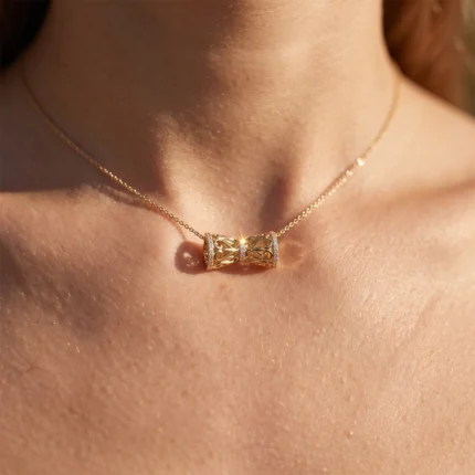 Gold necklace with an ornate filigree cylindrical pendant dotted with small diamonds.