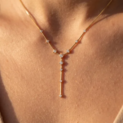 Gold necklace with a diamond-studded Y-shaped pendant resting on bare skin.