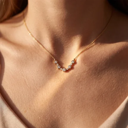 Close-up of a gold chain necklace with hexagon-shaped diamond settings resting on the collarbone.